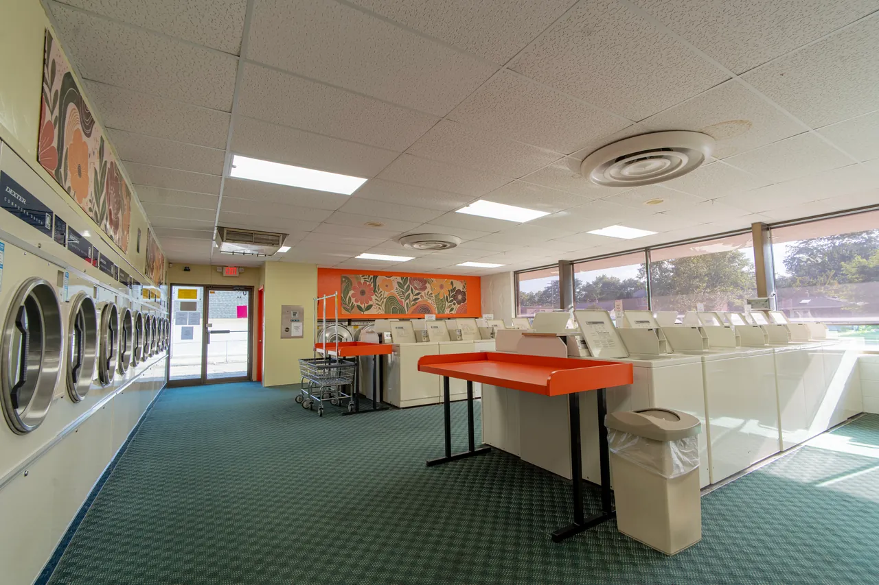 Long aisle of washers, folding tables, and laundry carts